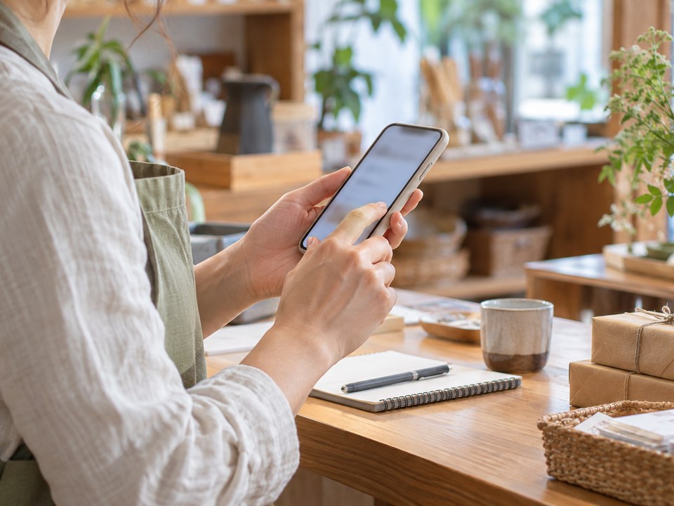 開業したばかりの方が店のカウンターでスマートフォンを使う手元